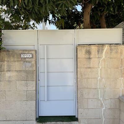 שער מתכת לבן במסגרת קיר אבן