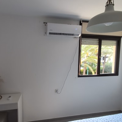חדר עם מזגן מותקן על הקיר ומנורה תלויה