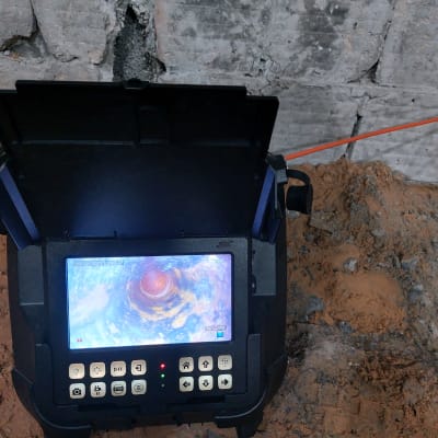 מכשיר איתור נזילות עם מסך תצוגה על רקע קיר בטון