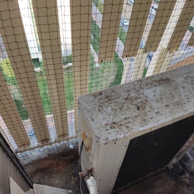 יחידת מזגן על מרפסת עם רשת למניעת יונים