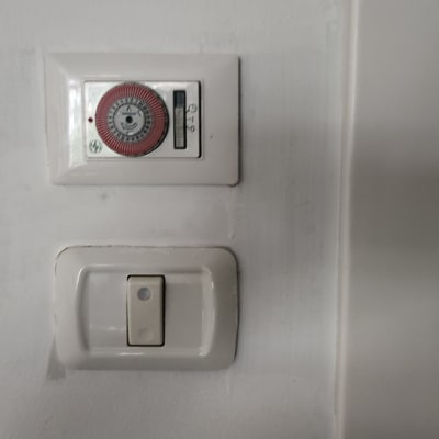 מתג חשמל ושעון טיימר על קיר לבן