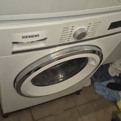 מכונת כביסה עם בגדים על הרצפה