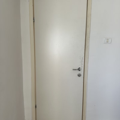 דלת לבנה עם ידית מתכת על קיר לבן