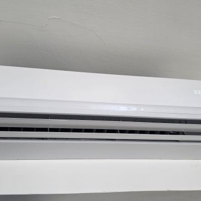 מזגן מותקן על קיר לבן עם תצוגת טמפרטורה