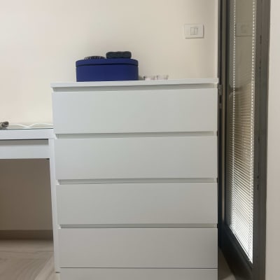 שידה לבנה ליד שולחן עם חפצים למעלה