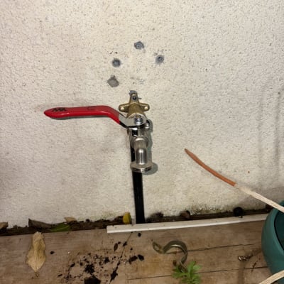 ברז מים מותקן על קיר חיצוני עם ידית אדומה