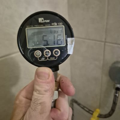 מד לחץ דיגיטלי מוחזק ביד, צינור מים ברקע