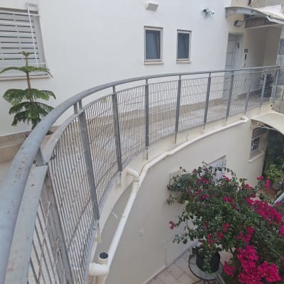 מעקה מתכת, צמחייה ופרחים במרפסת בניין