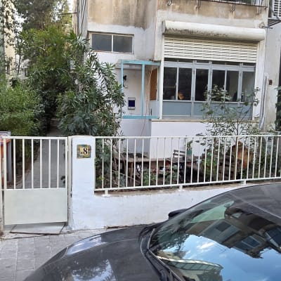 גדר לבנה עם שער קטן ליד בניין מגורים