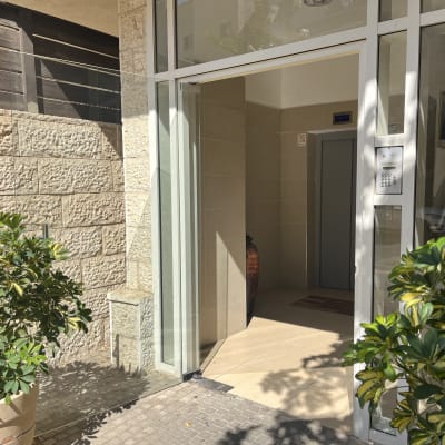 דלת זכוכית בכניסה לבניין עם צמחייה מסביב