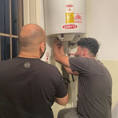 שני אנשים מתקנים דוד מים על קיר