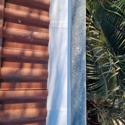 רעפים חומים על גג לצד פח מגולוון