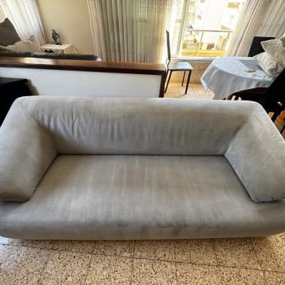 ספה אפורה בחדר מגורים עם שולחן וכיסאות ברקע