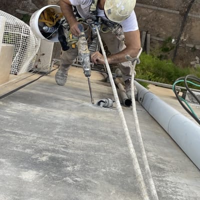 עובד בגובה קודח בקיר עם מקדחה חשמלית