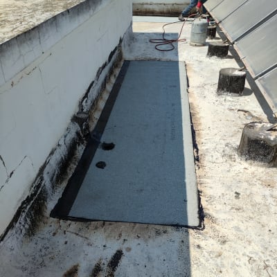 אדם מבצע איטום גג עם יריעות ביטומניות