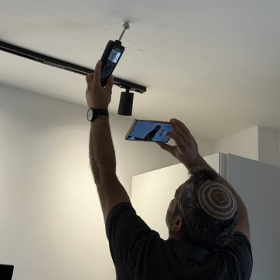 אדם מודד תקרה עם מכשיר מדידה