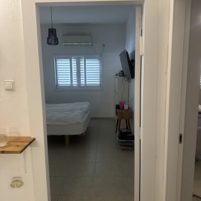 חדר שינה עם מיטה, מזגן וטלוויזיה על הקיר