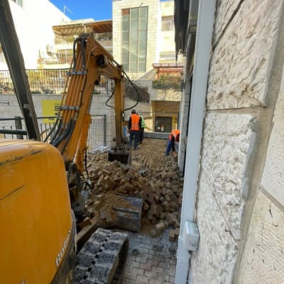 חפירה עם מחפרון וערימת אבנים באתר בנייה