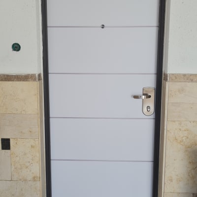 דלת לבנה עם ידית כסופה במסגרת שחורה