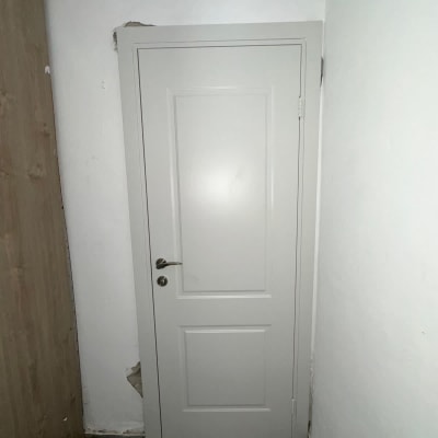 דלת לבנה עם ידית מתכת על קיר לבן