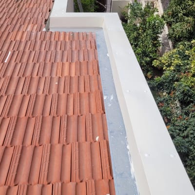 רעפים אדומים על גג עם תעלה לבנה