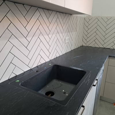 שיש שחור עם כיור מותקן, אריחים לבנים על הקיר