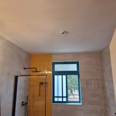 חדר אמבטיה עם אריחים צהובים ואפור, מקלחת וחלון