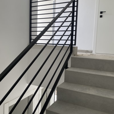 מעקה מתכת שחור על מדרגות בטון