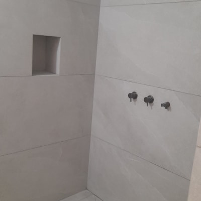 שיפוץ מקלחת עם אריחים אפורים וברזים שחורים