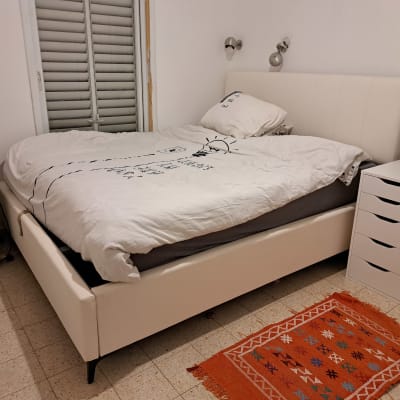 חדר שינה מסודר ומעוצב עם מיטה זוגית מוצעת ושידת לילה