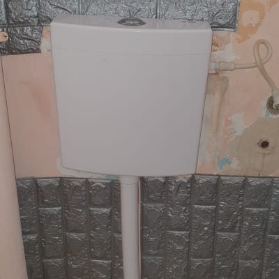 מיכל הדחה לבן עם צינור חיבור לקיר