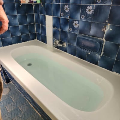 אמבטיה מלאה מים עם אריחים כחולים ודוגמת פרחים