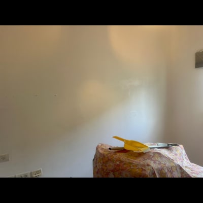 קיר צבוע עם כלי עבודה לצביעה על שולחן מכוסה