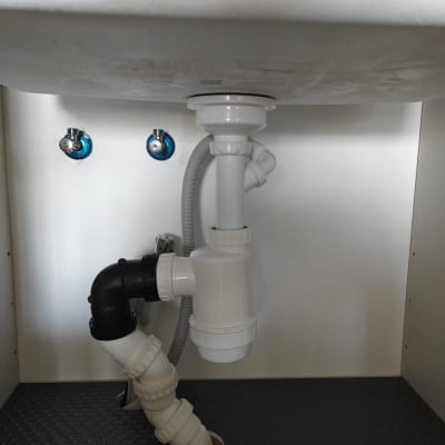 צנרת מתחת לכיור עם חיבורים ואביזרי אינסטלציה