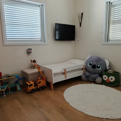 חדר ילדים עם מיטה, צעצועים ושטיח עגול