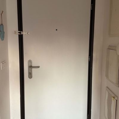 דלת לבנה עם ידית מתכת ומסגרת שחורה