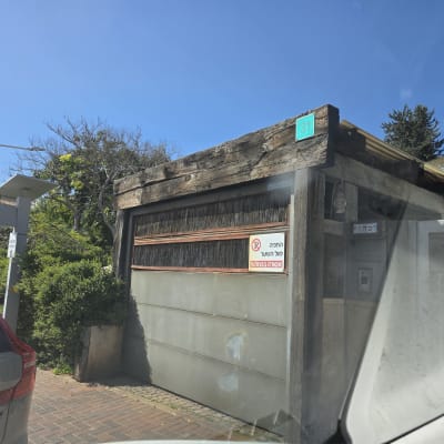 שער חשמלי עם שלט אזהרה ואזור חניה