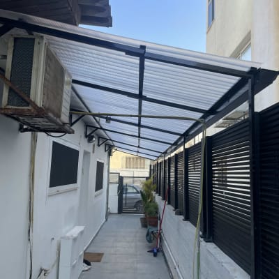 מסדרון חיצוני עם גג פלסטיק, עציצים ומטאטא