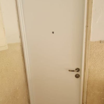 דלת לבנה עם ידית מתכת ועינית