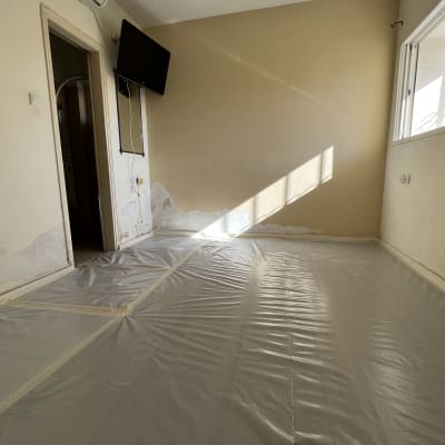 חדר עם קירות מתקלפים ורצפה מכוסה בניילון