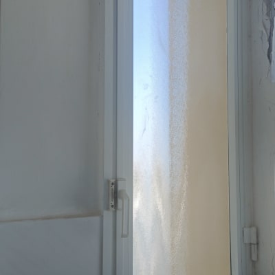 חלון זכוכית עם מסגרת לבנה וקיר מתקלף