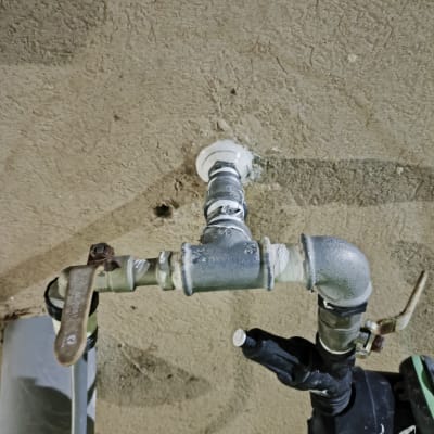 צינור מתכת עם ברזים ומחברים על קיר