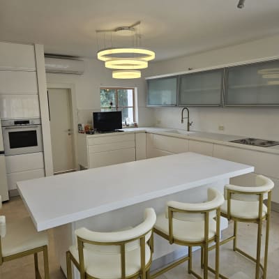 מטבח מודרני עם אי לבן וכיסאות בר