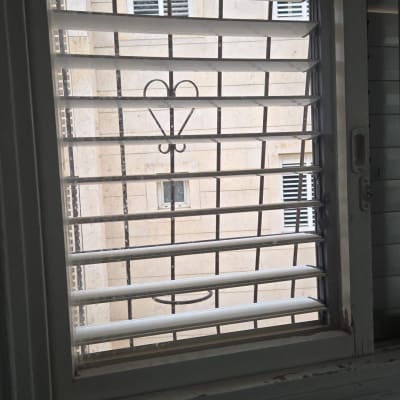 חלון עם סורגים ומבנה חיצוני ברקע