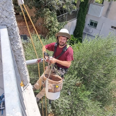 אדם עם כובע מגן תלוי על חבלים ליד קיר בטון