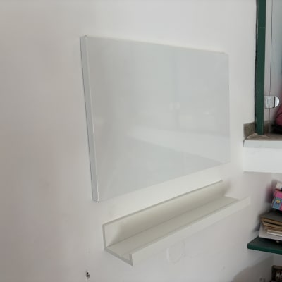 לוח לבן ומדף מותקנים על קיר לבן