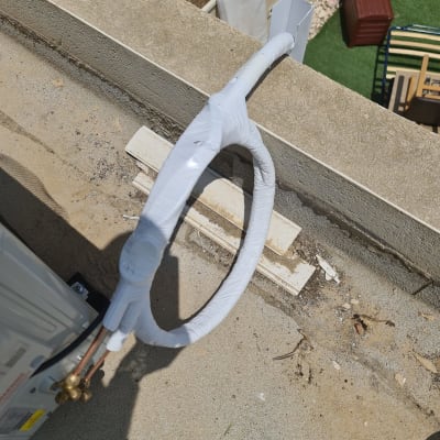 צינור מיזוג אוויר עטוף בלבן על גג בטון