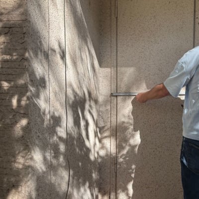 אדם מודד קיר חיצוני עם סרגל מתכת