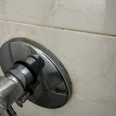 ברז מתכת על קיר אריחים עם סימני רטיבות