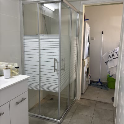 מקלחון זכוכית בחדר אמבטיה עם מכונת כביסה